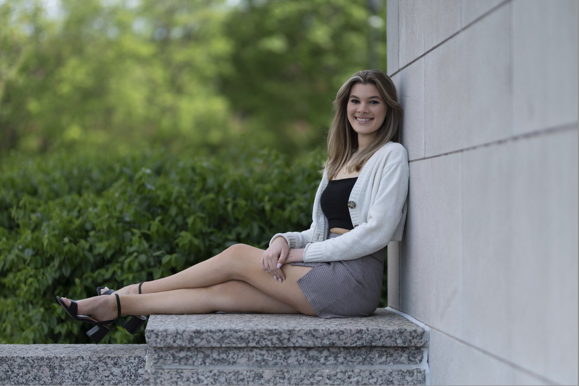 Senior girl seated by white columns in a cardigan and skirt — senior portraits, South Bend, Indiana