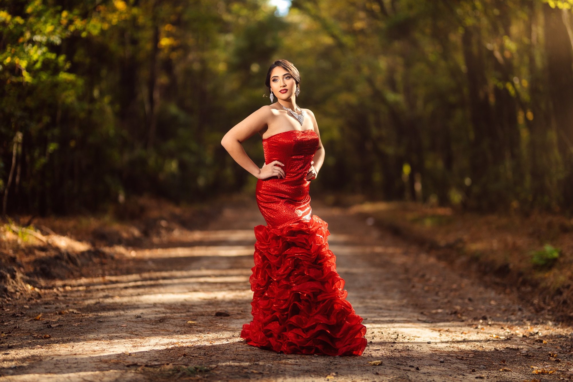 Senior girl in a red ruffled ballgown on a wooded road — senior portraits, Granger, Indiana