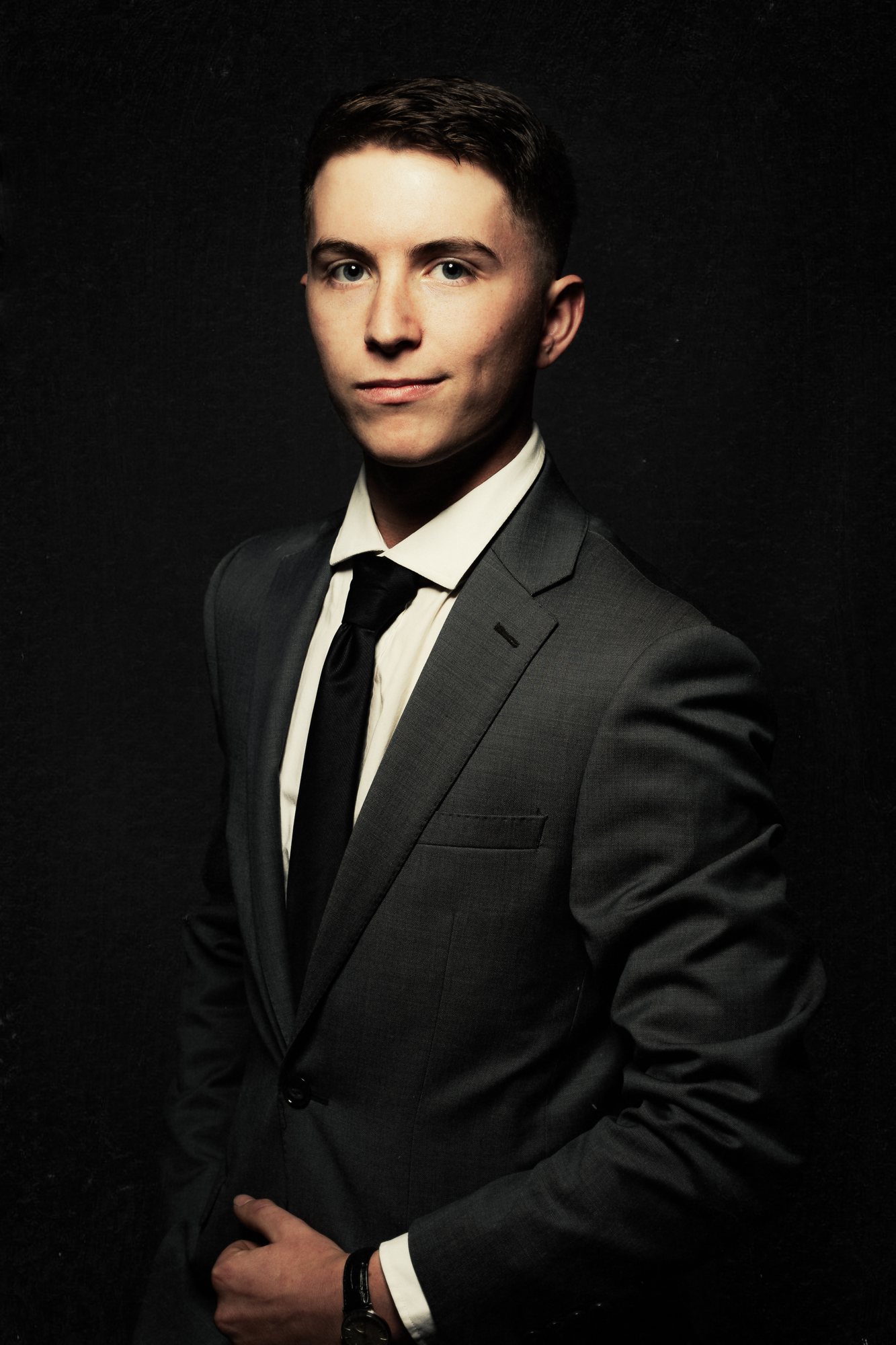 Senior guy in a black suit and tie on a dark studio backdrop — senior pictures, South Bend, Indiana