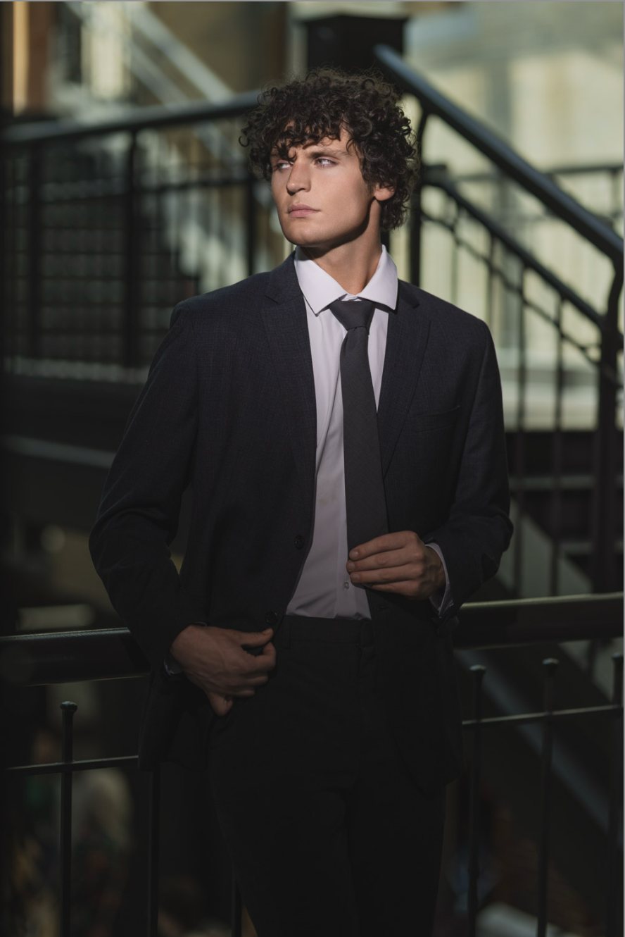 Styled senior guy in a dark suit on a modern staircase